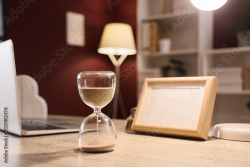 Foto Hourglass on desk in office at night, closeup