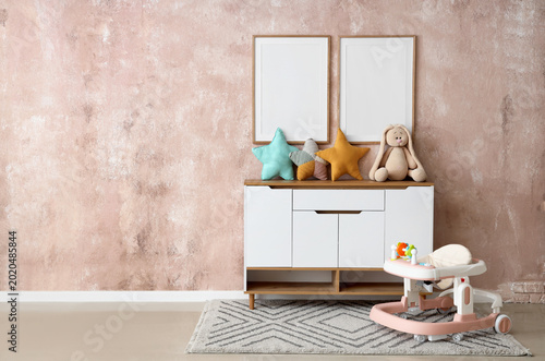 Fotografi Interior of children's room with baby walker, commode and blank frames