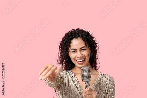 Konstfotografi Beautiful young happy African-American female singer with microphone pointing at