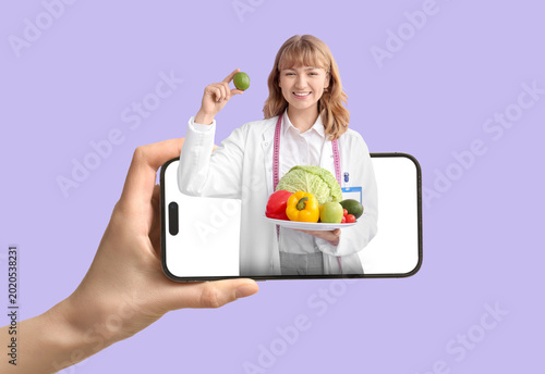 Young happy female nutritionist with fresh vegetables and measuring tape on p...