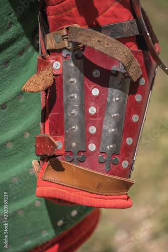 a pair of red medieval leggings (greaves), made of suede and reinforced with riveted steel strips. Materials: Quality suede and steel with a thickness of approximately 1.4 mm.