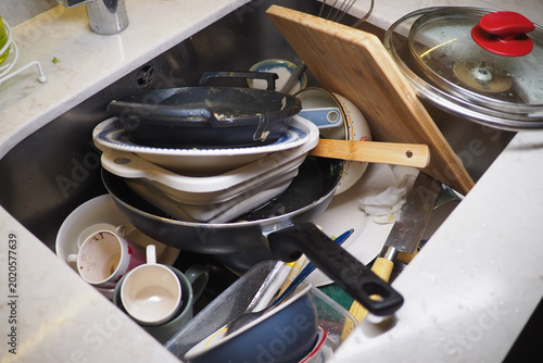 Quadro em tela Dirty dishes pile up in a kitchen sink during the evening
