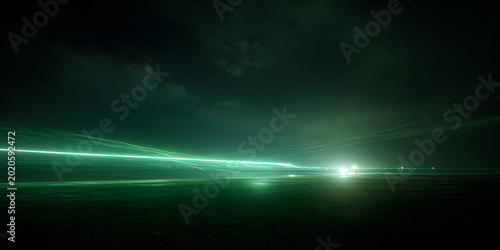 Green laser beam extending across dark coastal landscape at night captured using long exposure photography technique showing vibrant light trail atmosphere with illuminated horizon under cloudy sky.