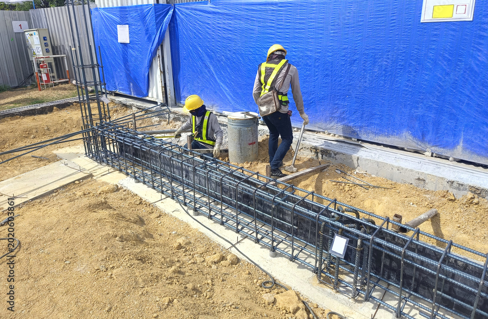 Ταπετσαρία Two construction workers tying steel reinforcement for ground beam inside industrial factory