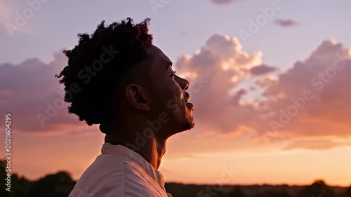 Man looking up at the vibrant sunset sky in a peaceful field