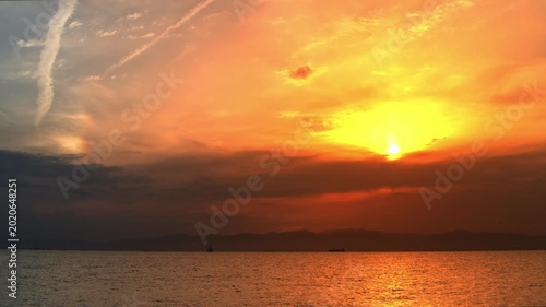 Dramatic Sunset Over Ocean Horizon with Orange Sky and Clouds