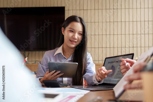 Schilderij op canvas Asian woman analyzing data on tablet and laptop in business meeting