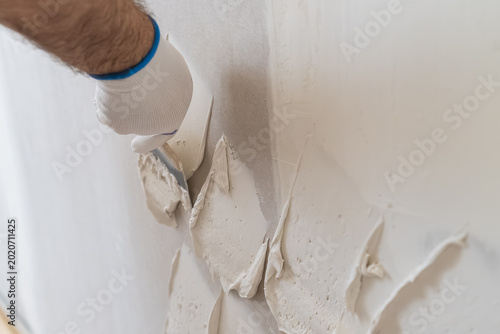 Fotografija Construction technician applying textured plaster to wall surface in renovation project