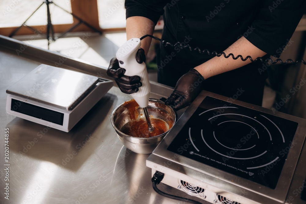 Wall Mural Chef blending caramel with immersion blender in kitchen