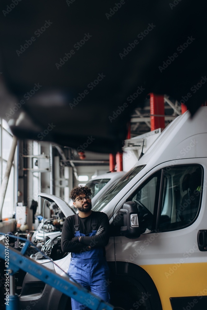 Naklejka premium Auto mechanic standing with arms crossed at service station