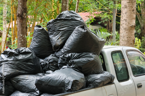 Принти на полотні Black plastic garbage bag piled high back of pickup truck parked near tree outdo