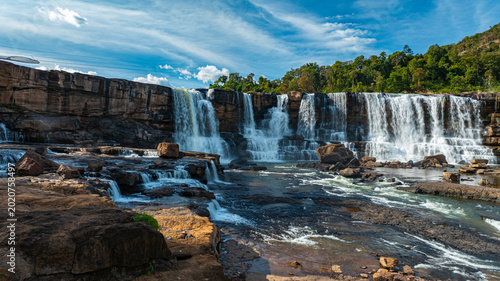 Canvas Print Aerial view of Sae Pong Lai Waterfall reveals a tropical river cascading over layered rock formations, surrounded by lush green forest and untouched wilderness