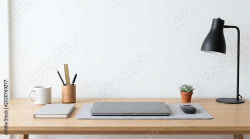 Laptop on wooden desk with lamp and office supplies in minimal workspace
