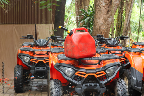 Foto Red gas container resting on front rack of orange all terrain vehicle parked out