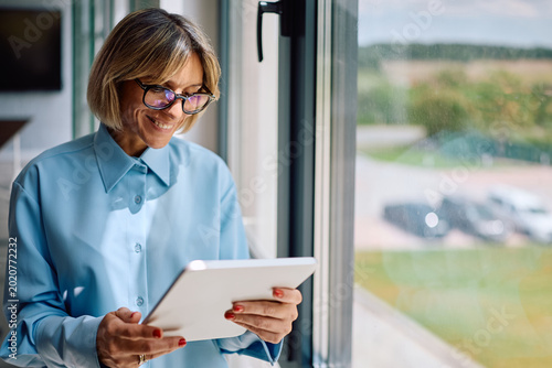 Принти на полотні Happy businesswoman reading email on touchpad while working in office