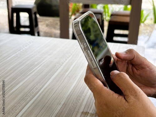 Fotografi An Asian woman holds a cell phone with a specially designed tempered glass screen protector that uses polarizing optical coating technology to make it difficult to spy on