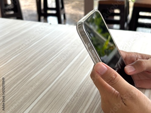 Quadro su tela An Asian woman holds a cell phone with a specially designed tempered glass screen protector that uses polarizing optical coating technology to make it difficult to spy on