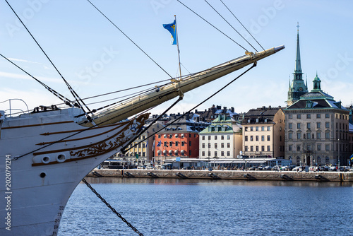Bilde på lerret Bow of a historic ship with Swedish flag, overlooking colorful buildings along t