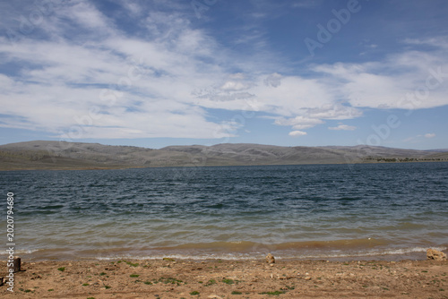 Fotografía Mountain lake shoreline under dramatic spring clouds