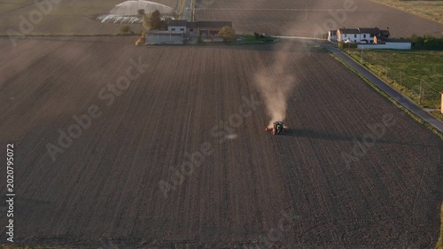 Tractor plowing a field at sunset in the Po Valley, Italy