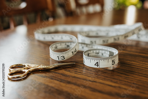 Close up of sewing tape measure laying on kitchen table with scissors