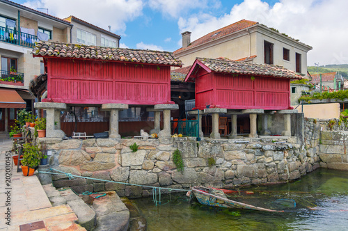 Фотография Traditional red wooden horreos on stone pillars by the sea in the fishing villag