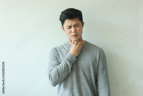 close up young asian man use hand to massage on neck to relieve symptom of pain from flu virus infections or lymphoma on white background for healthcare concept