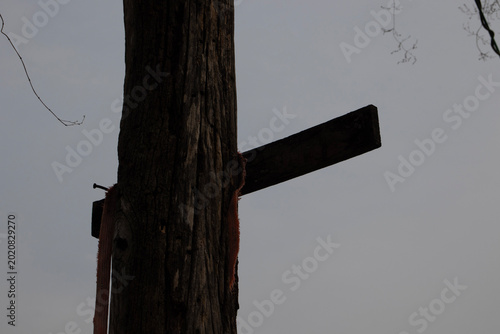 фотографія Silhouette of a weathered wooden post with a makeshift sign board against a grey overcast sky