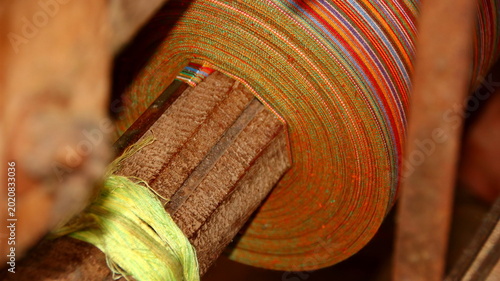 Intricate Textile Spool with Vivid Striped Fabric on Traditional Weaving Loom