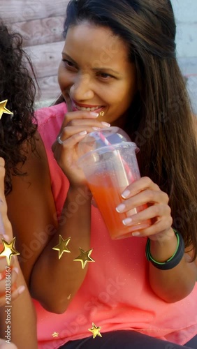 Vertical video: Woman lifting cup after friend holding drink, gold stars appearing for ads