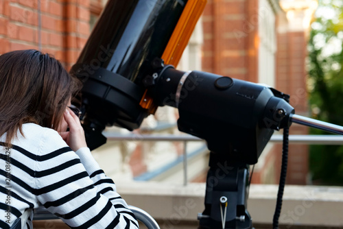 Canvastavla Person observing the sky through a telescope during a science lab open house, highlighting public engagement with astronomy