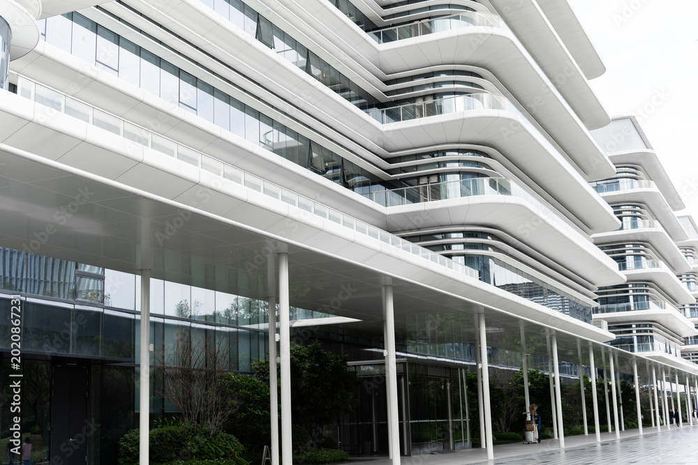 Fototapeta premium Modern Futuristic Office Building with Curved White Facade and Glass Windows in Urban Setting