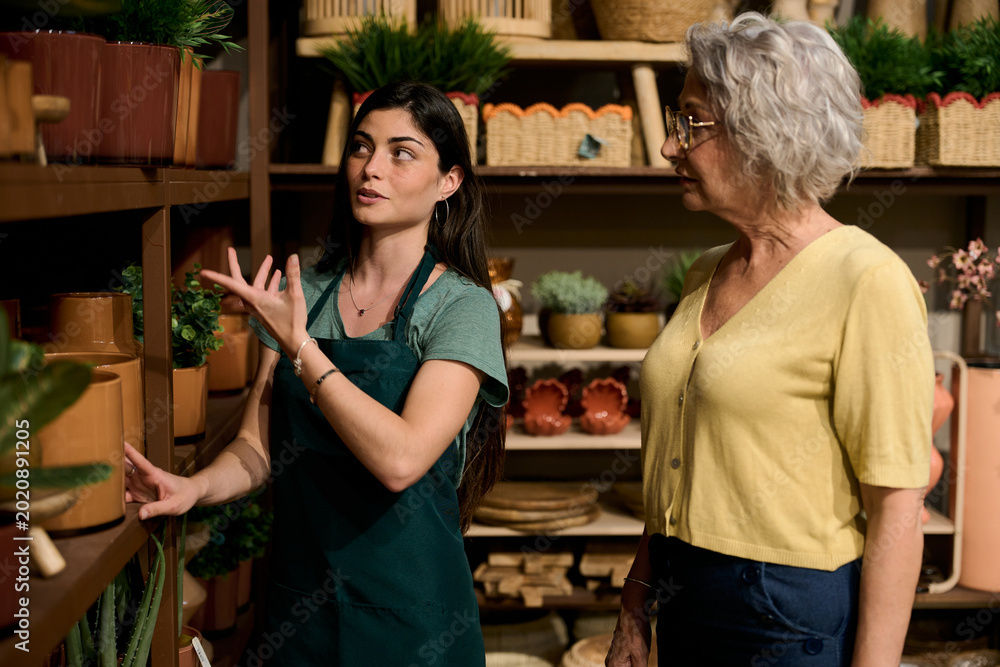 Obraz premium Employee helping customer choosing plants in small business