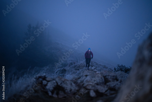 Tableau sur toile Solo Hiker With Headlamp Trekking a Foggy Mountain Trail at Night in Frosty Wint