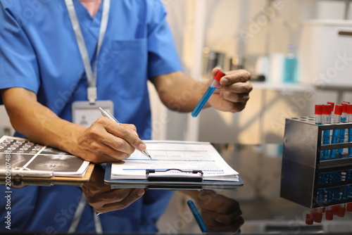 Professional doctor reviewing blood test laboratory results and examining medication at office desk, focusing on patient diagnosis, medical analysis, healthcare treatment planning