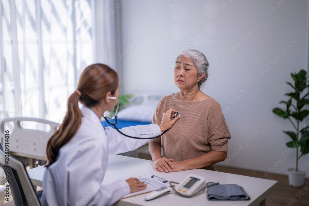 Fototapeta premium Doctor examining senior patient with stethoscope in hospital