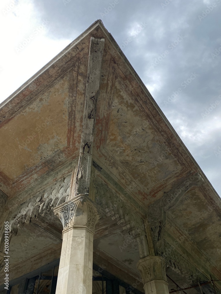 Fototapeta premium Architectural detail of ornate ancient column and ceiling with cloudy sky background