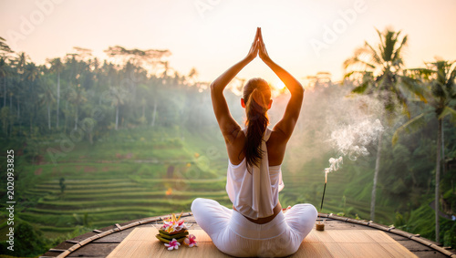 Woman practicing yoga meditation at sunrise overlooking rice terraces for wellness retreat brochure. mindfulness, mental health