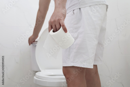 Foto Man holding toilet paper roll standing in front of toilet bowl
