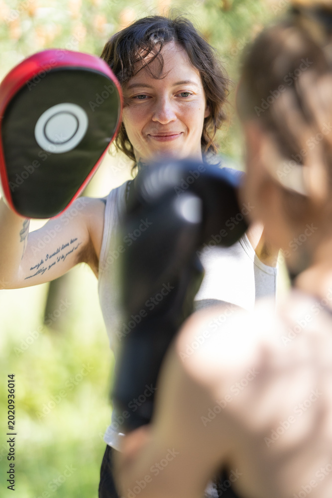 Obraz premium Woman holding boxing pad during outdoor training