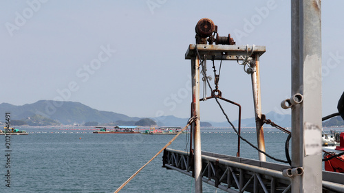 Foto Rusty Marine Winch and Aquaculture Farm in Coastal Waters