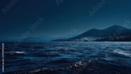 Dark Ocean Waves Under Moonlit Sky With Distant Mountains.