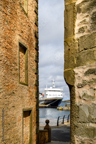 Tableau sur toile Blick durch den Spalt zwischen zwei Backsteinwänden auf ein Schiff im Hafen von