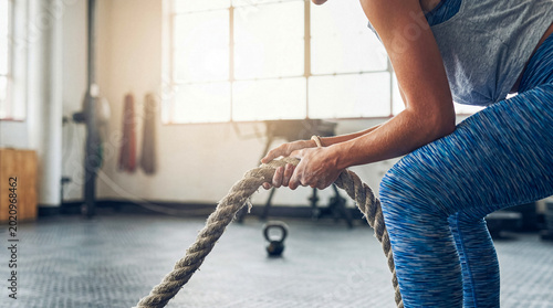 фотографія Powerful woman gripping a heavy battle rope, ready for an intense functional training workout in a gym