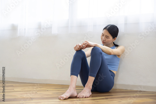 Foto Asian Woman in Yoga Wear Sitting on Floor with Exhausted Expression