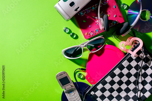 Retro millennium aesthetic composition with flip phone and checkered bag