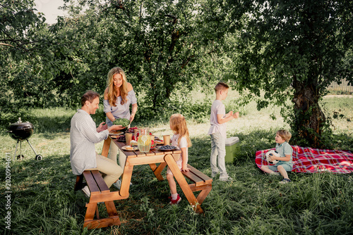 Photos Family enjoying a relaxed outdoor picnic in a sunny backyard with parents and ch