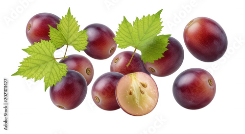 Fresh red grapes with bright green vine leaves isolated on a black background, including one grape sliced in half showing internal seeds
