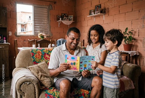 Happy Brazilian father receiving a handmade Father's Day card from his young daughter and son at home