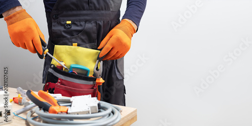 Electrician taking tools out of belt. Banner with copy space.